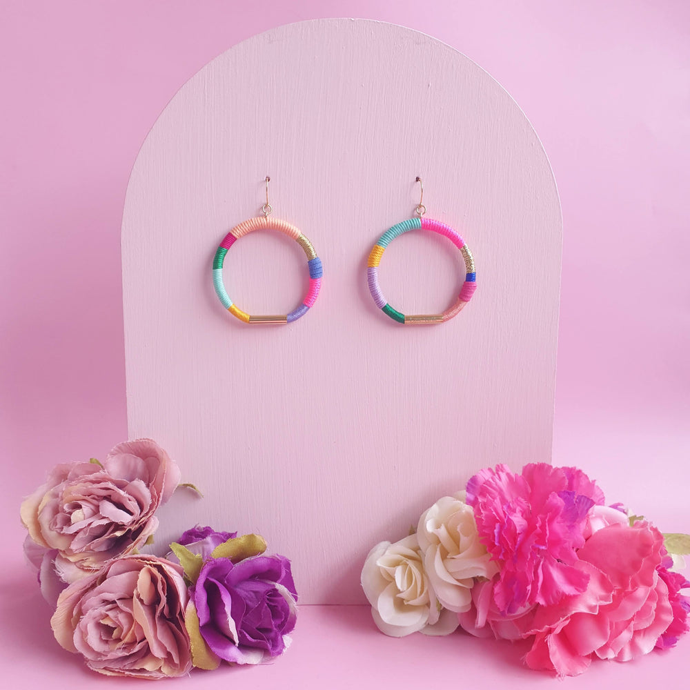 Colorful hoop earrings wrapped in pastel and bold thread with gold-tone accents