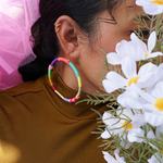 Model is wearing colourful hoop earrings that accentuate a mix bold and vibrant colours