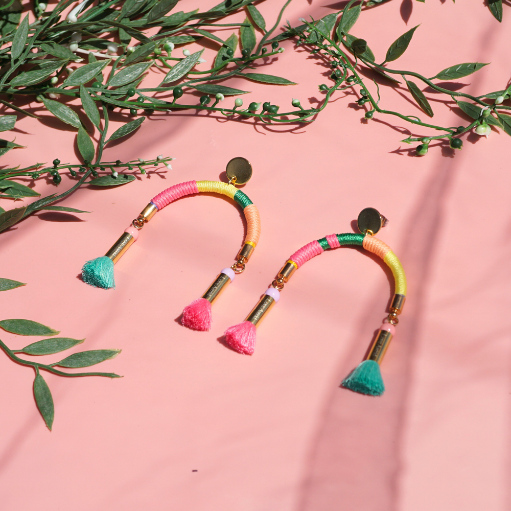 Arch-shaped earrings wrapped in colourful pastel threads featuring hand-dyed pink and mint tassels at each end.