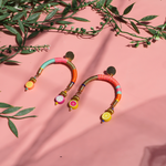 Colourful arch-shaped earrings with gold, pink, blue, and orange threads, gold-plated beads, and fruity beads at each end.