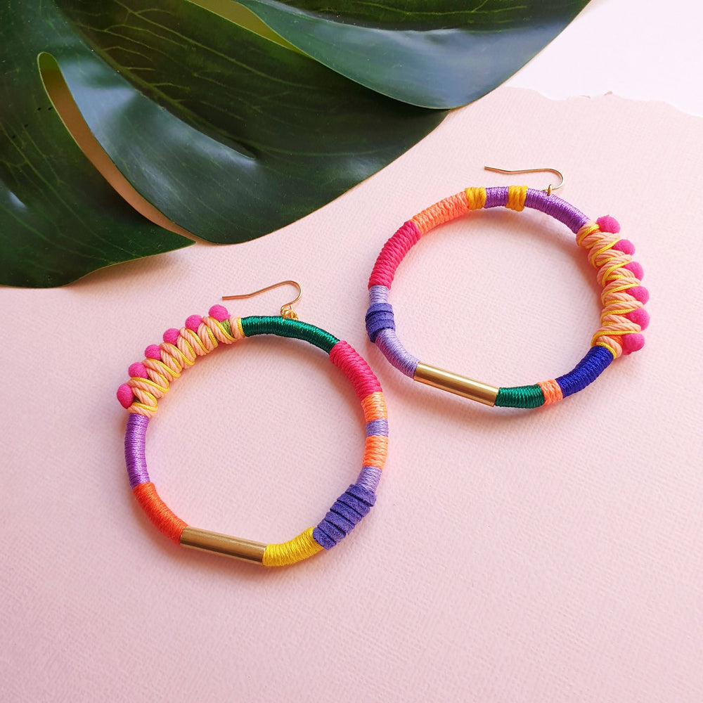 Handmade colourful hoop earrings wrapped in vibrant fibre threads, featuring unique woven details accented with gold hardware. Lightweight and comfortable statement jewellery. perfect for bold 