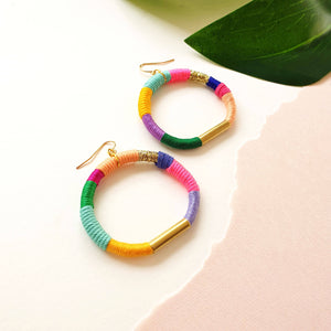 Colorful hoop earrings wrapped in pastel and bold thread with gold-tone accents