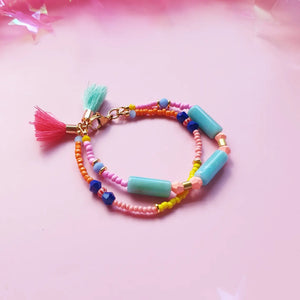 Beaded bracelet with green resin tubes as the main accent, accented by orange, peach, and pink beads for a vibrant, colourful design. Finished with a tassel in a random colour.