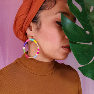 Model is wearing colourful hoop earrings that accentuate a mix bold and vibrant colours