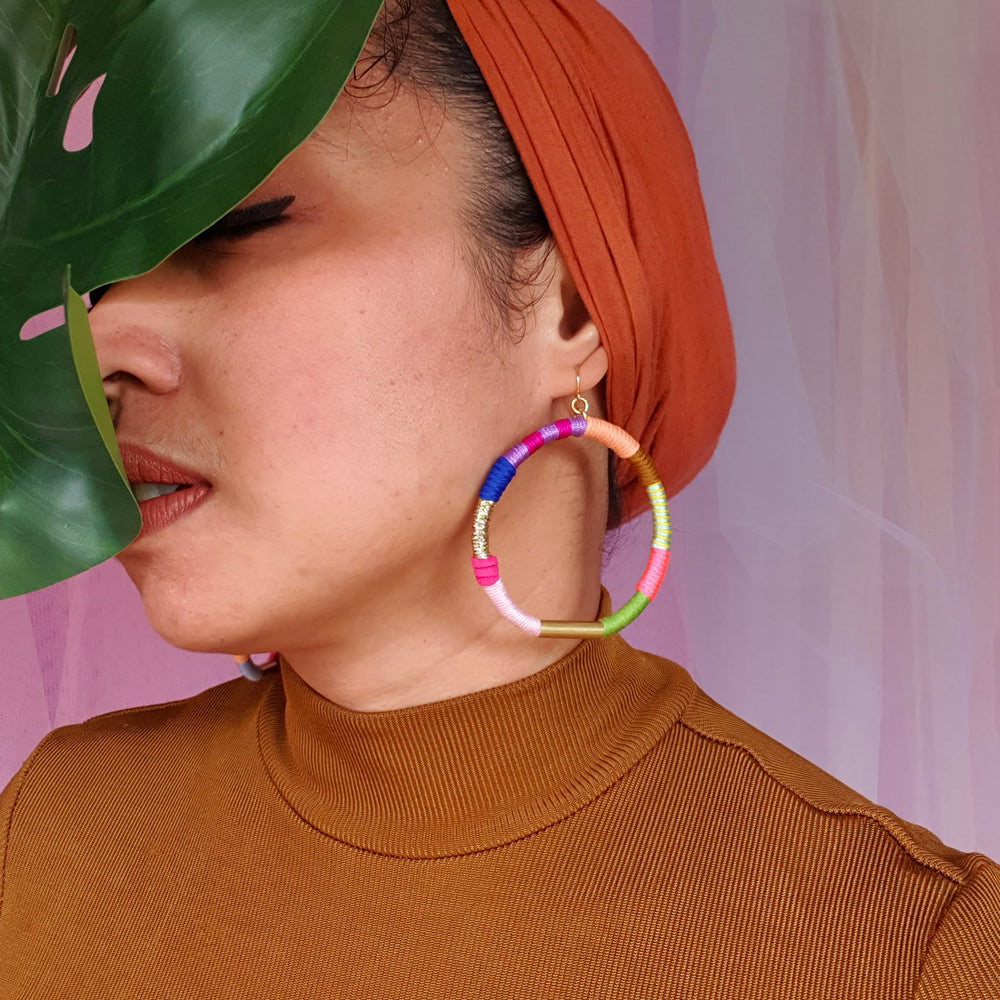 Model is wearing colourful hoop earrings that accentuate a mix bold and vibrant colours