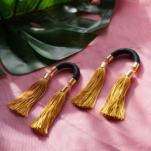 Trendy black and gold tassel earrings with a unique arched design, featuring silky gold tassels that sway with every movement.