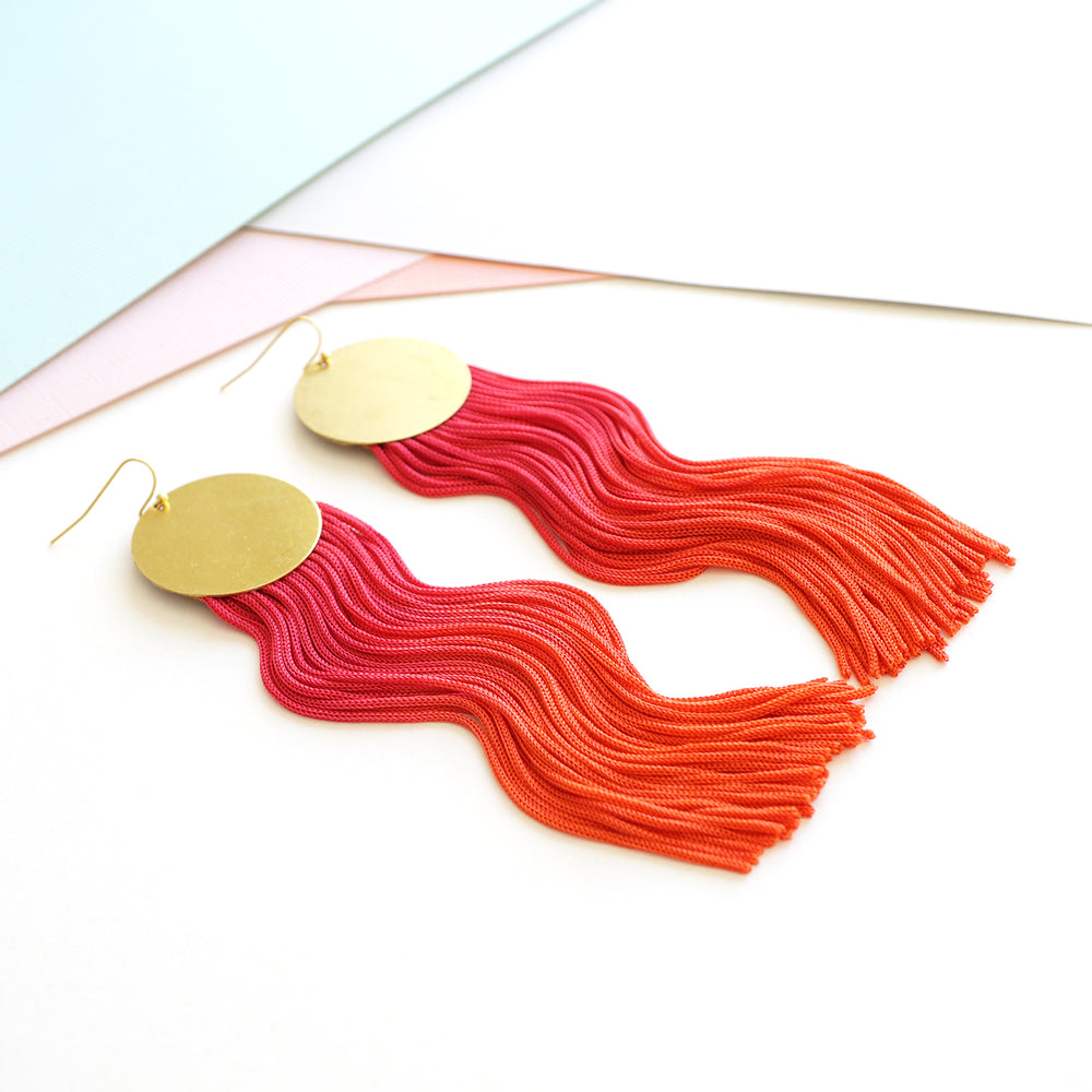 Hand-dyed pink and orange ombre tassel earrings with gold-plated round pendants, featuring a bold, vibrant, and elegant design. Lightweight and eye-catching, perfect for statement styling.