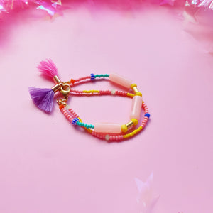 Beaded bracelet featuring peach resin tubes as the main accent, complemented by orange, pink, yellow, and green beads for a vibrant, colourful design. Finished with a tassel in a random colour