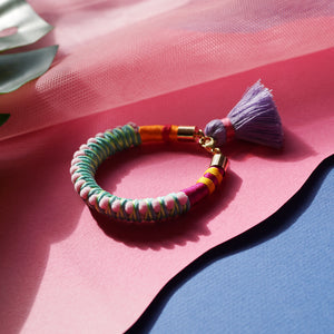 A fun and colourful bracelet designed with delicate pink pom-poms, intricate thread details, and a playful tassel charm