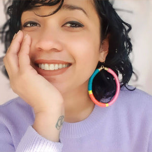 Model is wearing hoop earrings featuring a beautiful combination of pink, green, and yellow pastel colours for a soft, colourful look.