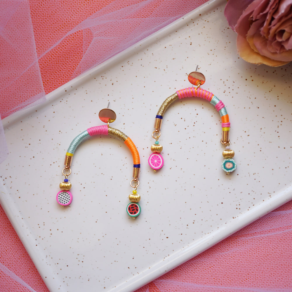 Colourful arch-shaped earrings with gold, pink, blue, and orange threads, gold-plated beads, and fruity beads at each end.