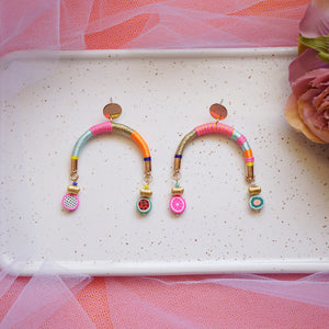 Colourful arch-shaped earrings with gold, pink, blue, and orange threads, gold-plated beads, and fruity beads at each end.